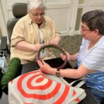 Judy helps another resident of Paul's Run to use a loom