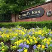 The entrance of Paul's Run with a bed of yellow and lavander flowers in front of the sign.