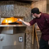A Paul's Run dining team member bakes pizza in the woodfire stove.