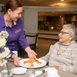 A dining team member hands a resident her meal at Paul's Run Retirement Community in Northeast Philadelphia