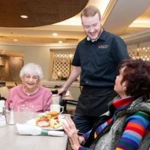 A Paul's Run waiter serves food to a resident in the dining room.